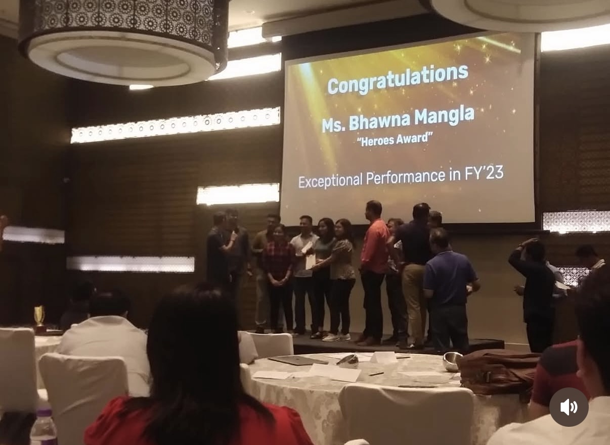 Award ceremony stage with a screen reading: Congratulations Ms. Bhawna Mangla, Heroes Award, Exceptional Performance in FY'23, with recipients gathered on stage